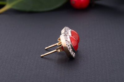 A statement pair of vintage mid-century earrings made of solid 18 kt gold. These head-turning earrings have a classic geometric design and are set with two large red coral cabochons.  The coral cabochons measure 0.35 inch in diameter each and are in a lovely vintage condition with no surface wear.