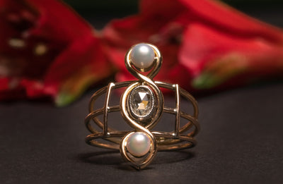 A very unusual Victorian revival three-stones ring, featuring two snow-white pearls and a chunky oval rose cut diamond of circa 0.8 ct.