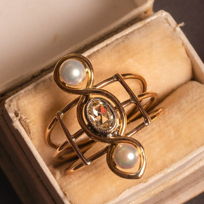 A very unusual Victorian revival three-stones ring, featuring two snow-white pearls and a chunky oval rose cut diamond of circa 0.8 ct.